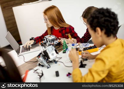 Group of happy kids programming electric toys and robots at robotics classroom