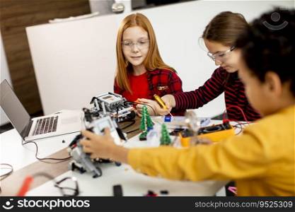 Group of happy kids programming electric toys and robots at robotics classroom