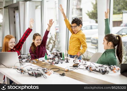 Group of happy kids programming electric toys and robots at robotics classroom