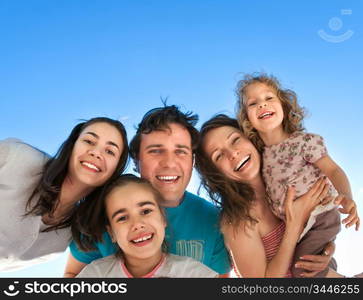 Group of happy smiling friends: man, women and kids having fun outdoors against blue sky background. Summer vacations concept