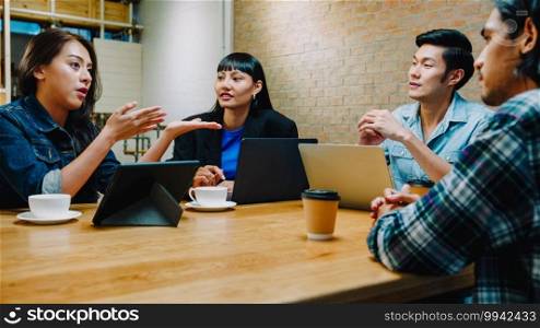 Group of happy young Asia business coworkers using laptop in team casual meeting, startup project discussion at cafe restaurant. Coffee shop holiday activity, modern friendship lifestyle concept.