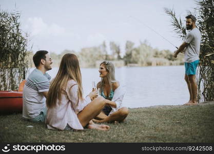 Group of happy young friends enjoying the nature on the lakeside