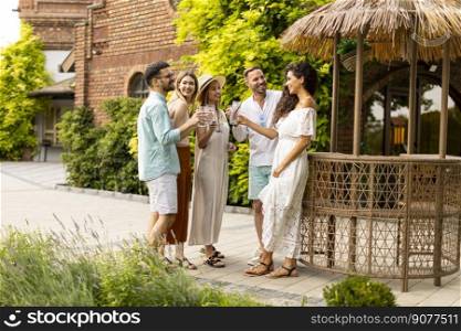 Group of happy young people cheering and having fun outdoors with drinks