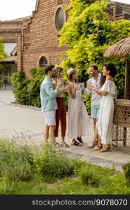 Group of happy young people cheering and having fun outdoors with drinks