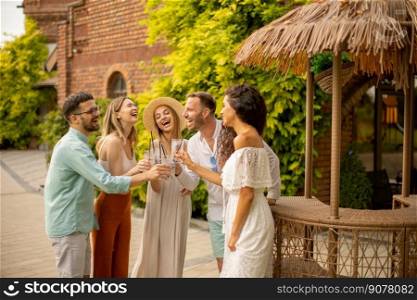 Group of happy young people cheering and having fun outdoors with drinks