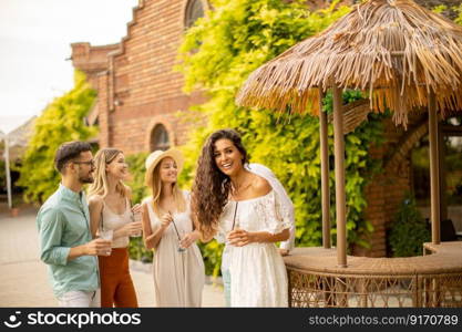 Group of happy young people cheering and having fun outdoors with drinks