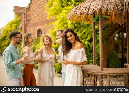 Group of happy young people cheering and having fun outdoors with drinks