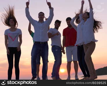 group of happy young people dancing and have fun on party in modern home bacony with sunset and ocean in background