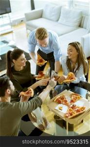 Group of happy young people eating pizza and drinking cider in the modern interior