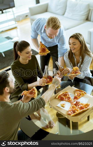 Group of happy young people eating pizza and drinking cider in the modern interior