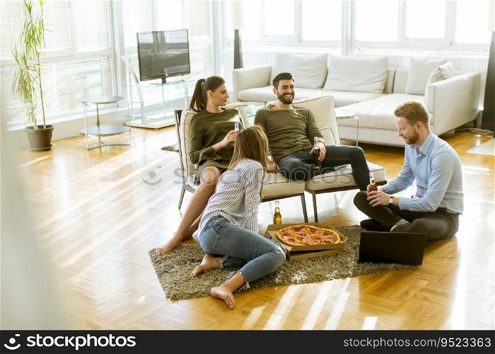 Group of happy young people eating pizza and drinking cider in the modern interior