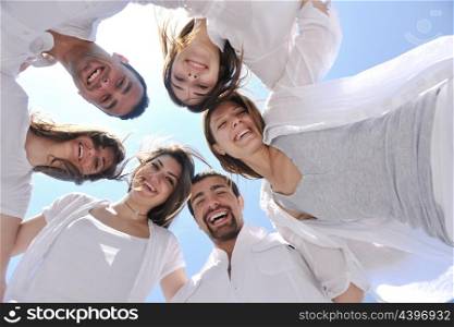 Group of happy young people in circle at beach have fun and smile