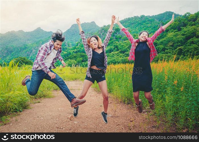 Group of happy young people jumping in the air while traveling in mountain and nature trail. Travel and outdoors lifestyle concept.