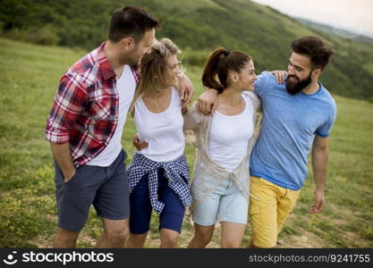 Group of happy young people walking in the summer field