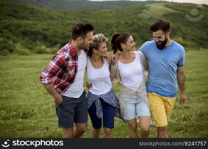 Group of happy young people walking in the summer field