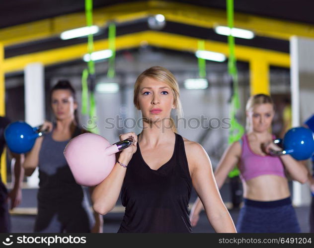 group of healthy young athletes doing exercises with kettlebells at crossfitness studio. athletes doing exercises with kettlebells