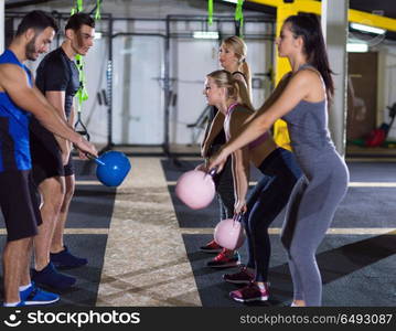 group of healthy young athletes doing exercises with kettlebells at crossfitness studio. athletes doing exercises with kettlebells