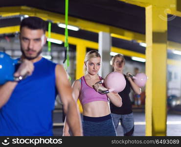 group of healthy young athletes doing exercises with kettlebells at crossfitness studio. athletes doing exercises with kettlebells