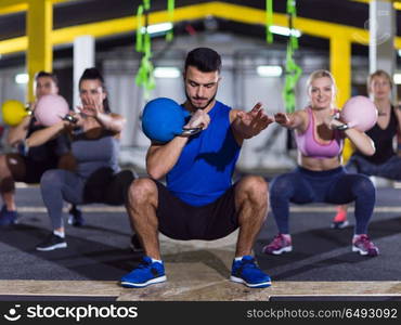 group of healthy young athletes doing exercises with kettlebells at crossfitness studio. athletes doing exercises with kettlebells