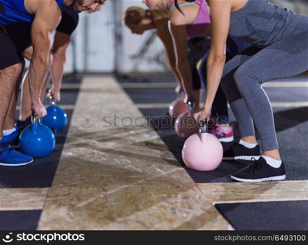 group of healthy young athletes doing exercises with kettlebells at crossfitness studio. athletes doing exercises with kettlebells