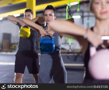 group of healthy young athletes doing exercises with kettlebells at crossfitness studio. athletes doing exercises with kettlebells