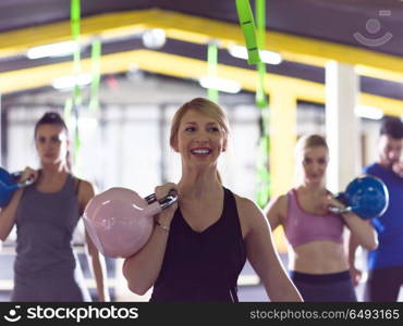 group of healthy young athletes doing exercises with kettlebells at crossfitness studio. athletes doing exercises with kettlebells