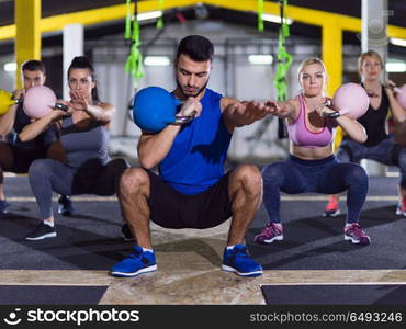 group of healthy young athletes doing exercises with kettlebells at crossfitness studio. athletes doing exercises with kettlebells