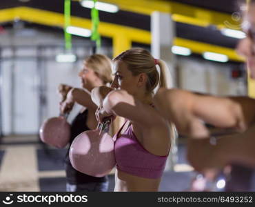 group of healthy young athletes doing exercises with kettlebells at crossfitness studio. athletes doing exercises with kettlebells