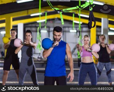 group of healthy young athletes doing exercises with kettlebells at crossfitness studio. athletes doing exercises with kettlebells