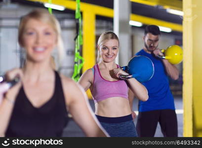 group of healthy young athletes doing exercises with kettlebells at crossfitness studio. athletes doing exercises with kettlebells