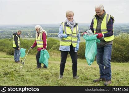 Group Of Helpful Seniors Collecting Litter In Countryside