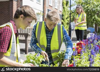 Group Of Helpful Teenagers Planting And Tidying Communal Flower Beds