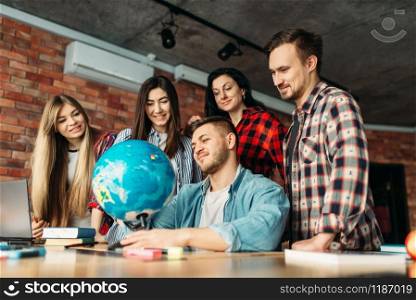 Group of highschool students looking at the globe, teamwork project. People studying together, university youth learning subject