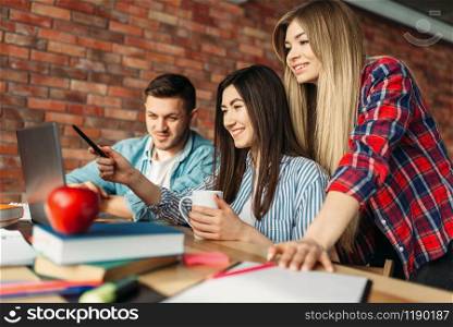 Group of highschool students looking on laptop together. People with computer search information in internet, teamwork, joint project