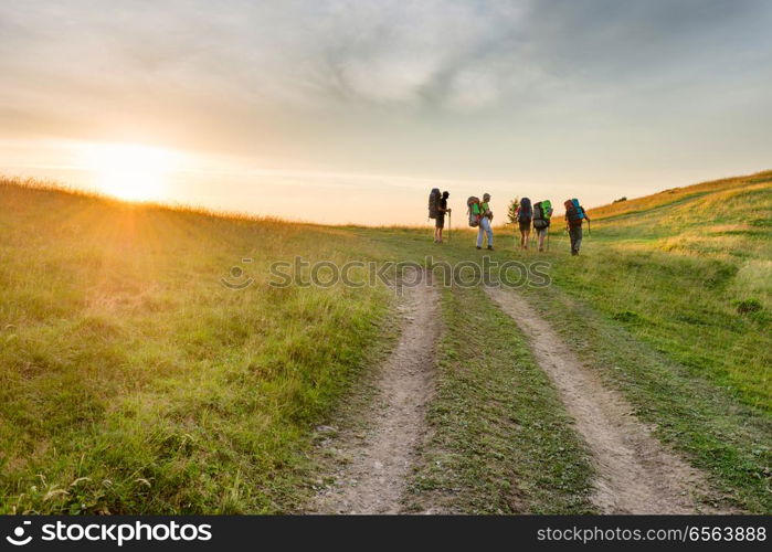 Group of hiking friends in the sunset mountains. Group of hiking friends on the road in the sunset mountains