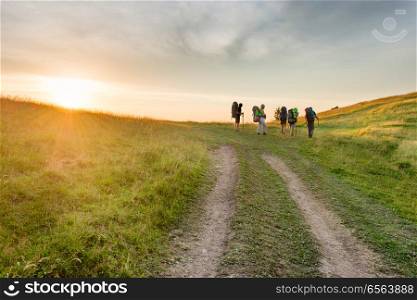 Group of hiking friends in the sunset mountains. Group of hiking friends on the road in the sunset mountains