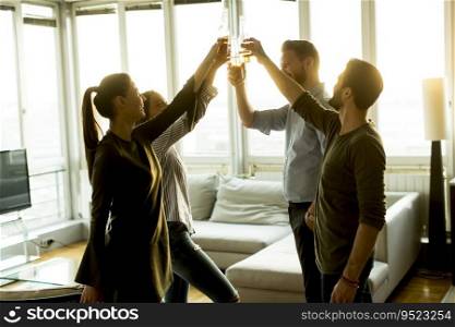 Group of male and female friends having fun at home and toasting with cider bottles