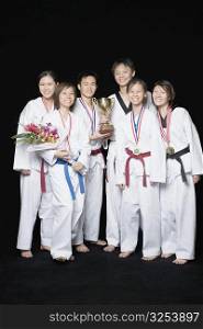 Group of martial arts players standing with their medals and trophies