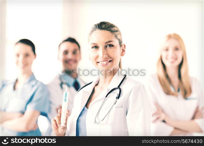 group of medics with female doctor holding syringe with injection