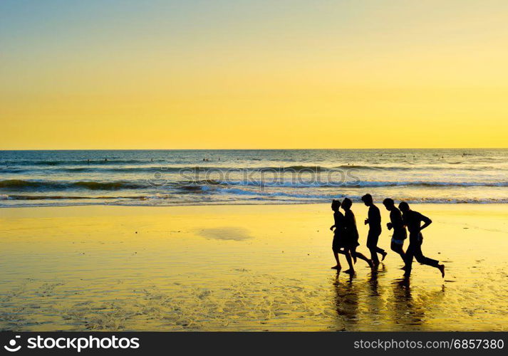 Group of men running on the beach at sunset. Bali island, Indonesia