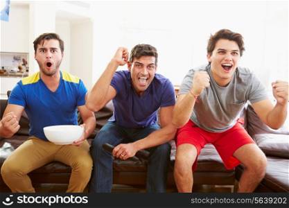 Group Of Men Sitting On Sofa Watching Sport Together