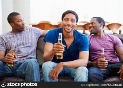 Group Of Men Sitting On Sofa Watching TV Together
