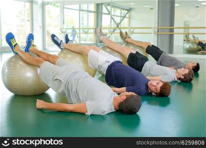 Group of men with legs raised on aerobic balls