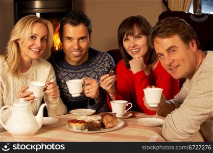 Group Of Middle Aged Couples Enjoying Tea And Cake Together