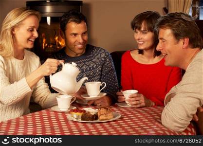 Group Of Middle Aged Couples Enjoying Tea And Cake Together
