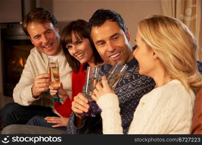 Group Of Middle Aged Couples Sitting On Sofa With Champagne