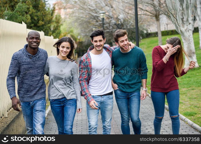 Group of multi-ethnic young people having fun together outdoors in urban background. group of people walking together