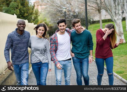 Group of multi-ethnic young people having fun together outdoors in urban background. group of people walking together