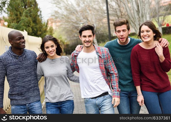 Group of multi-ethnic young people having fun together outdoors in urban background. group of people walking together