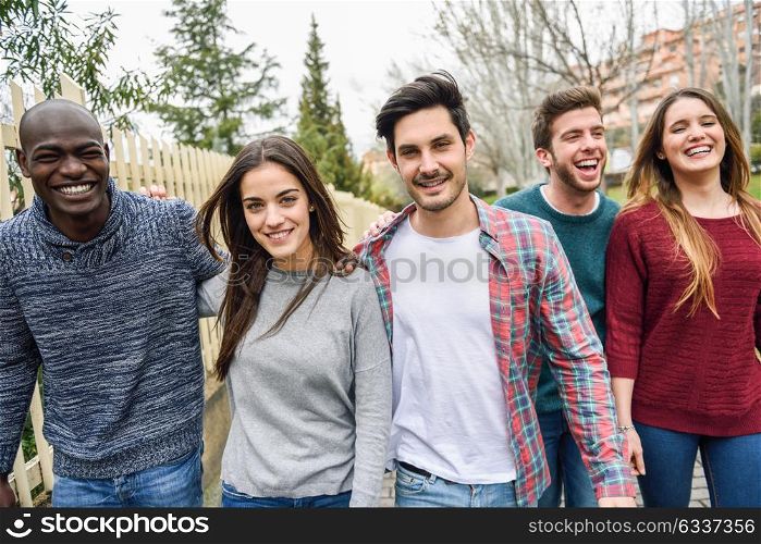 Group of multi-ethnic young people laughing together outdoors in urban background. group of people walking together wearing casual clothes